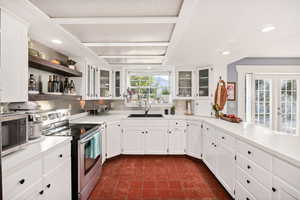 Kitchen featuring appliances with stainless steel finishes, white cabinetry, open shelves, light countertops, and recessed lighting