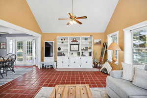 Living area featuring french doors to the outside, high vaulted ceiling, a ceiling fan, and concrete tile floors