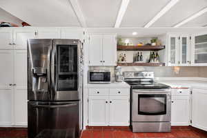 Kitchen with open shelves, white cabinets, appliances with stainless steel finishes, and backsplash