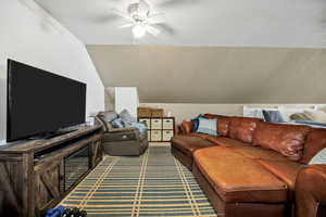 Living room/Loft area featuring lofted ceiling, a textured ceiling, and a ceiling fan