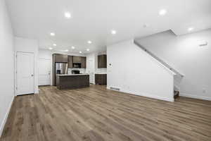 Unfurnished living room featuring recessed lighting, light wood-style flooring, and stairs