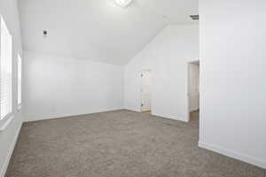 Additional living space with high vaulted ceiling and carpet floors