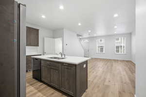 Kitchen featuring dark brown cabinets, light wood-style floors, recessed lighting, a kitchen island with sink, and open floor plan