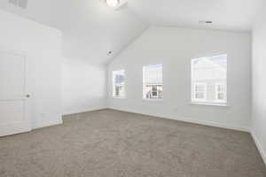 Empty room featuring light colored carpet and high vaulted ceiling