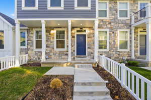 View of exterior entry with stone siding and a porch