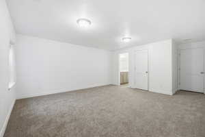Unfurnished bedroom featuring light carpet, a textured ceiling, and ensuite bathroom