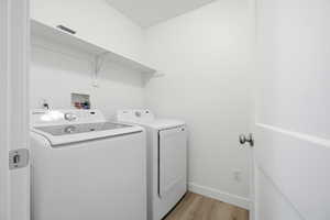 Laundry room featuring light wood finished floors and washing machine and clothes dryer