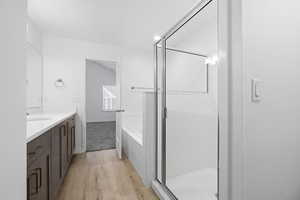 Bathroom featuring a bath, vanity, light wood-style floors, and a stall shower