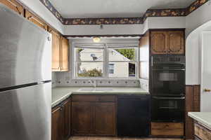Kitchen with black appliances, light countertops, backsplash, and arched walkways