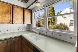 Kitchen with tasteful backsplash, light countertops, and brown cabinets