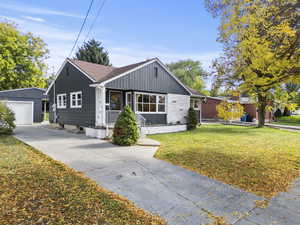 View of front of home with an outdoor structure, a front lawn, driveway, board and batten siding, and a detached garage