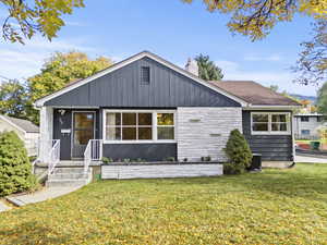 View of front of house with a front lawn, a chimney, and stone siding