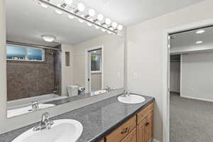 Bathroom featuring double vanity, shower / bath combination, and light carpet