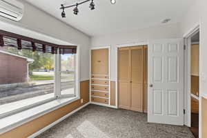 Unfurnished bedroom with light colored carpet, a wall unit AC, and a closet