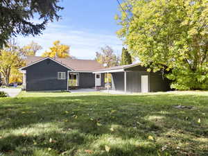 Back of property featuring a patio, a lawn, and roof with shingles