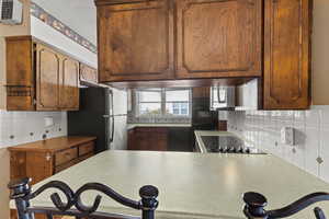 Kitchen featuring tasteful backsplash, a peninsula, black appliances, a kitchen bar, and brown cabinetry