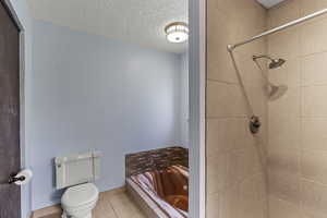 Bathroom featuring a bath, a textured ceiling, tiled shower, and tile patterned flooring
