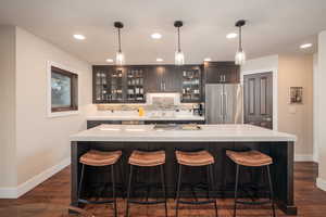 Bar featuring high quality fridge, hanging light fixtures, backsplash, recessed lighting, and glass insert cabinets