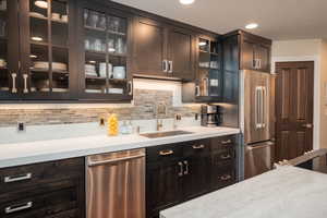 Kitchen with appliances with stainless steel finishes, dark brown cabinetry, decorative backsplash, and recessed lighting
