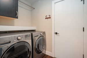 Laundry room featuring cabinet space, dark wood-type flooring, and washer and dryer