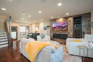 Living room featuring stairs, a large fireplace, recessed lighting, and hardwood / wood-style flooring