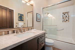 Bathroom with vanity and combined bath / shower with glass door