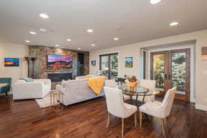 Dining space featuring healthy amount of natural light, dark wood finished floors, recessed lighting, a fireplace, and french doors