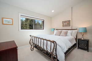 Bedroom with vaulted ceiling, light carpet, and recessed lighting