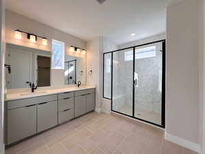 Bathroom with double vanity, light tile patterned floors, a shower stall, and recessed lighting