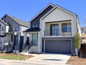 Contemporary home with an attached garage, driveway, and stucco siding