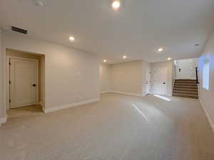 Below grade area featuring stairway, recessed lighting, and light carpet
