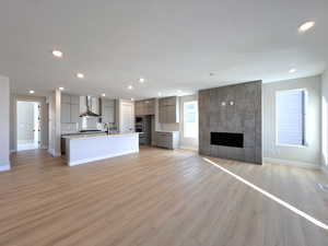 Unfurnished living room featuring light wood finished floors, a fireplace, a textured ceiling, and recessed lighting