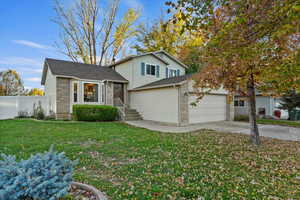 Tri-level home with brick siding, driveway, roof with shingles, and a garage