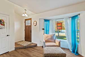 Foyer with wood finished floors, lofted ceiling, and a chandelier