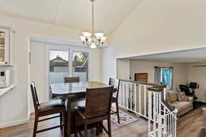 Dining room featuring light wood-type flooring, a chandelier, and lofted ceiling