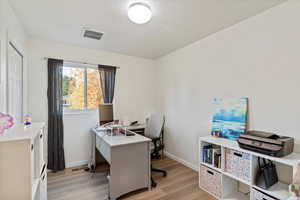 Office space with light wood-style floors and a textured ceiling