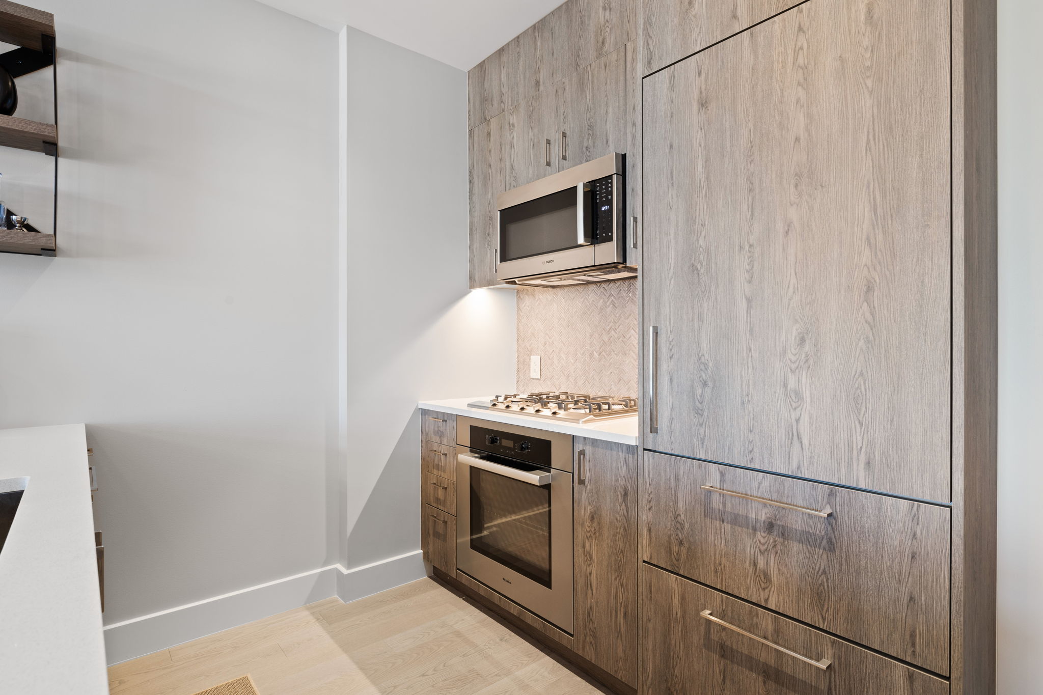 Kitchen featuring tasteful backsplash, modern cabinets, stainless steel appliances, light countertops, and light wood finished floors