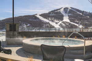 View of pool featuring an outdoor hot tub, a mountain view, and a patio area