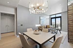 Dining room featuring a chandelier, a wall of windows, recessed lighting, and light wood-style floors