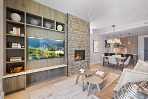 Living area with wood-floors, built in features, and a stone fireplace