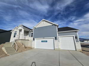 Craftsman house with stone siding, driveway, board and batten siding, stairway, and an attached garage