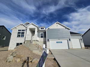 Craftsman-style home with stone siding, driveway, board and batten siding, and an attached garage