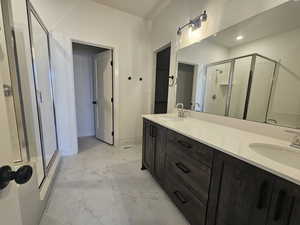 Full bath featuring double vanity, a shower stall, light marble finish floors, and recessed lighting