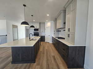 Kitchen with a center island with sink, pendant lighting, light wood-style flooring, backsplash, and appliances with stainless steel finishes
