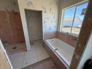 Full bath featuring wallpapered walls, a garden tub, and light tile patterned floors