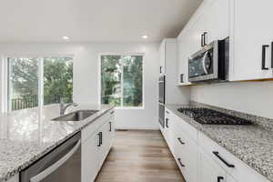 Kitchen with stainless steel appliances, white cabinetry, light wood-style floors, and recessed lighting