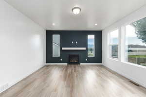Unfurnished living room featuring a fireplace, light wood-style floors, and recessed lighting
