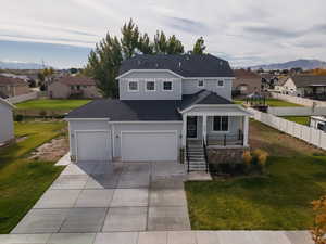 Traditional-style house featuring a residential view, covered porch, driveway, and roof with shingles