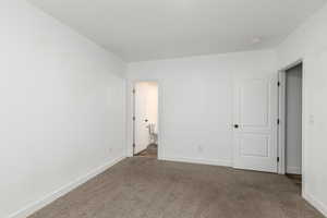 Unfurnished bedroom with dark colored carpet and connected bathroom