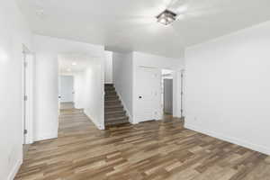 Unfurnished living room featuring wood finished floors and stairway